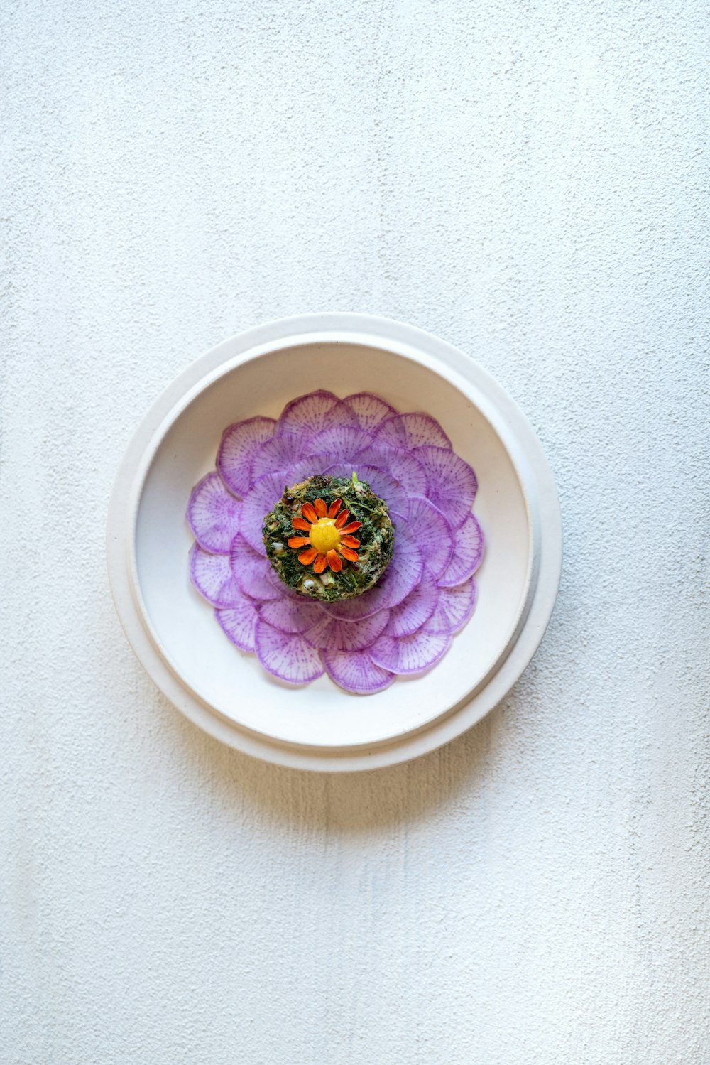 a white bowl with a purple flower in it