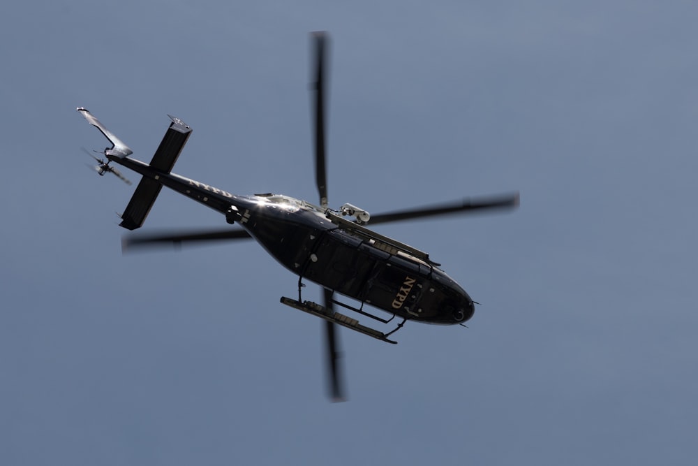 a helicopter flying through a blue sky with a propeller