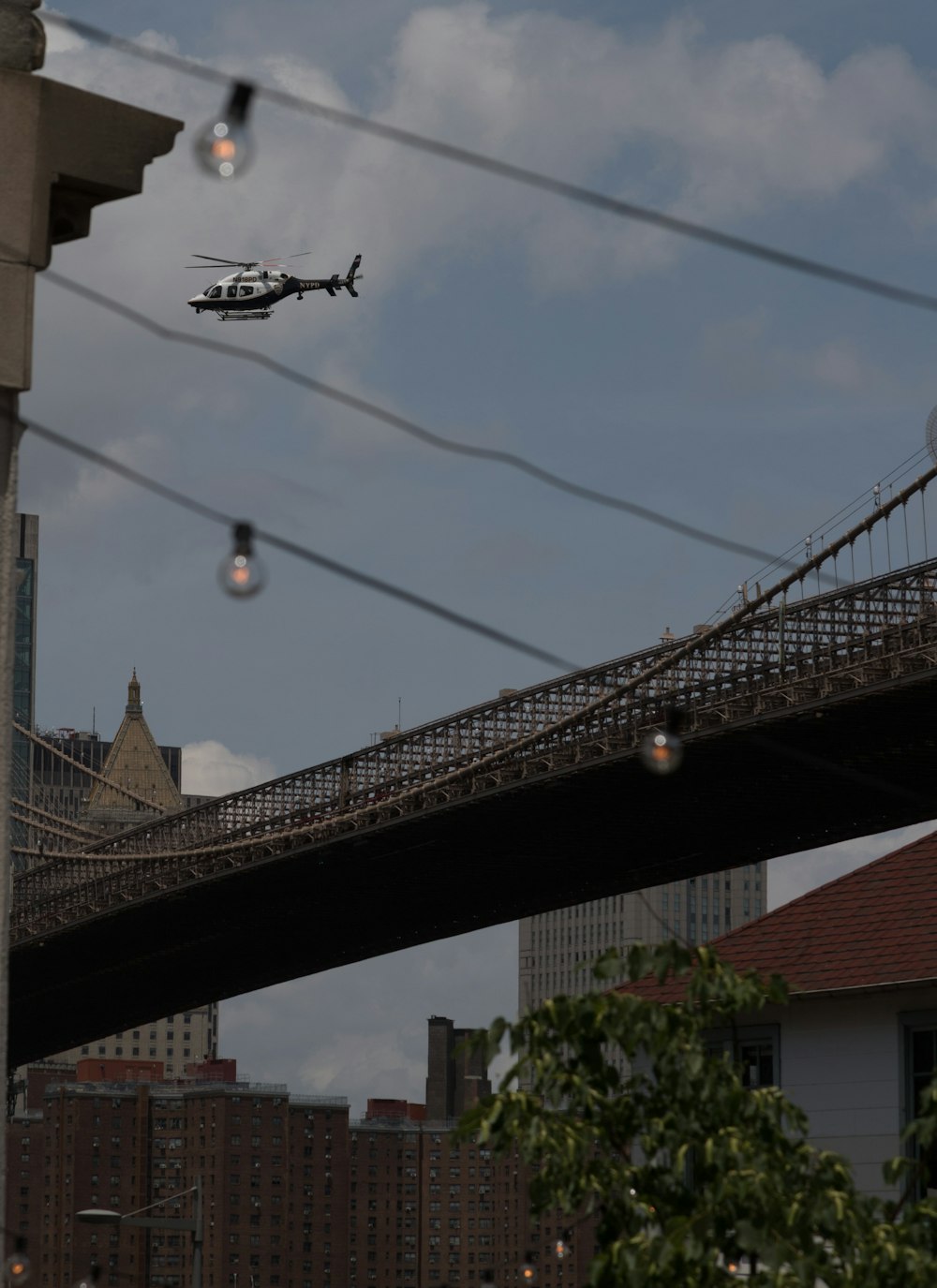 a helicopter flying over a bridge with a city in the background