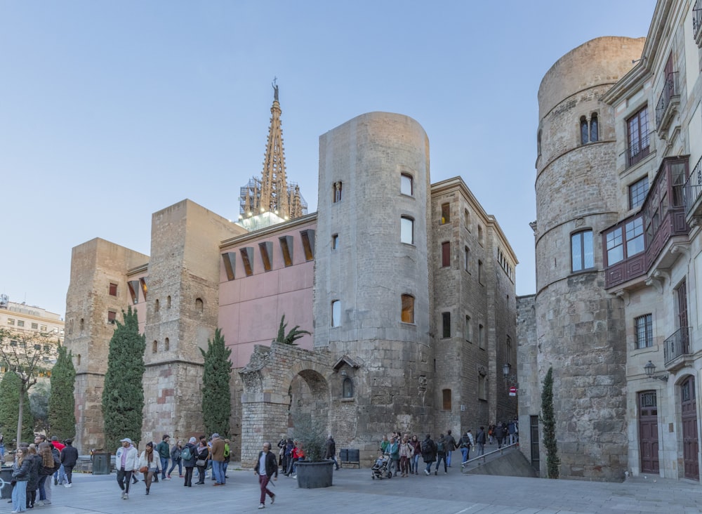 a group of people walking around a stone building