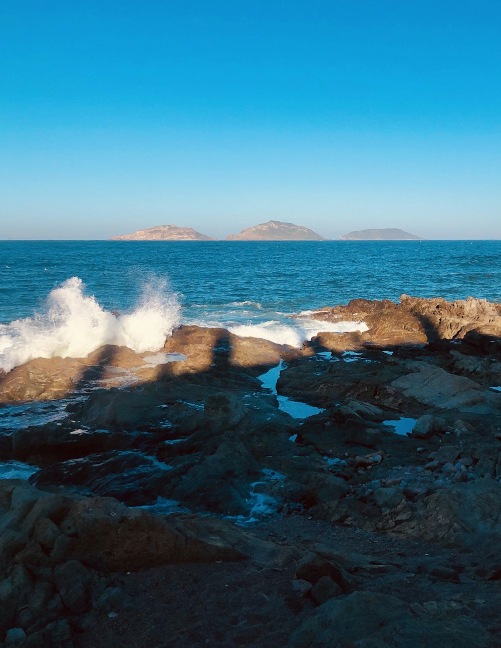 a person standing on a rocky beach next to the ocean