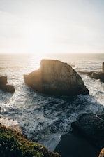 A rugged coastline at sunset with waves crashing against rocky cliffs, highlighting the wild beauty of Bettys Bay.