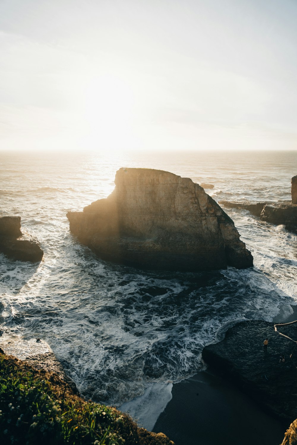 the sun is shining over the ocean and rocks