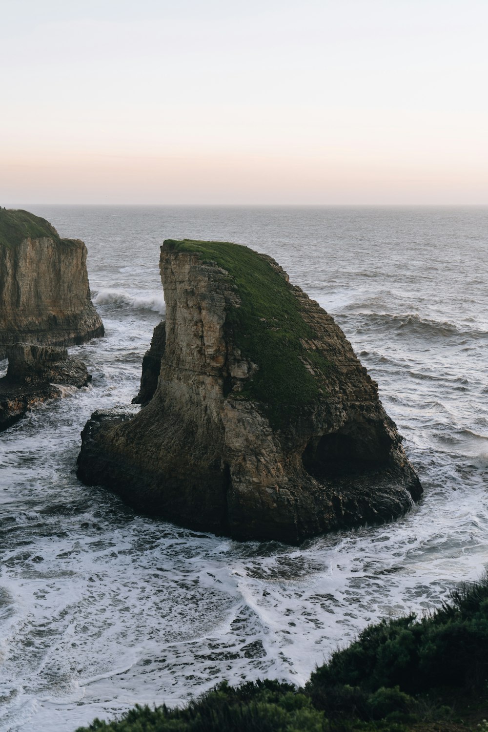 a large rock sticking out of the ocean