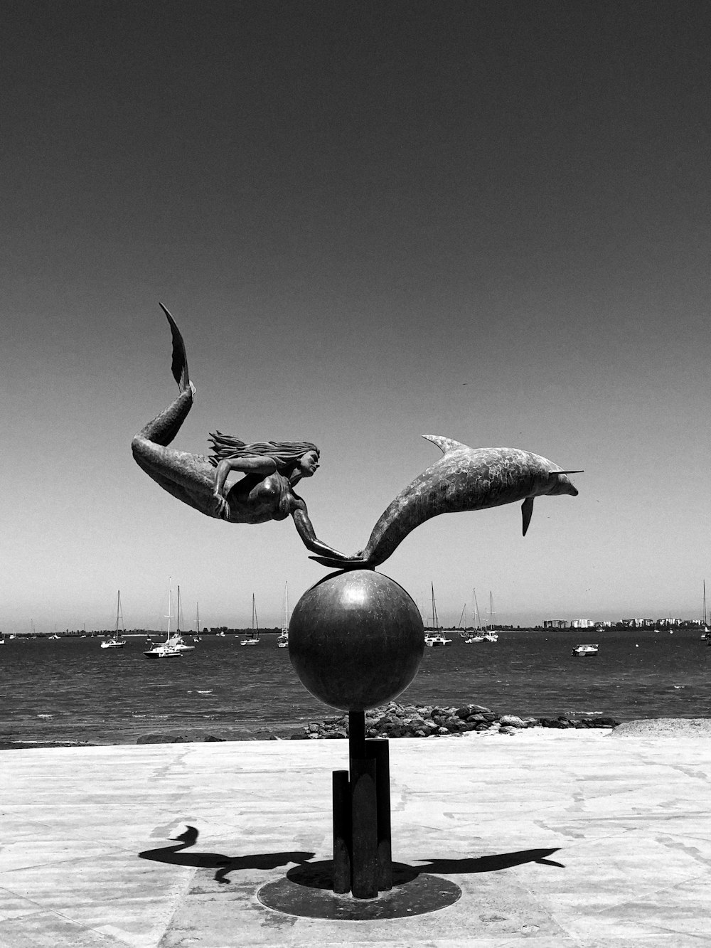 a black and white photo of a statue of two dolphins
