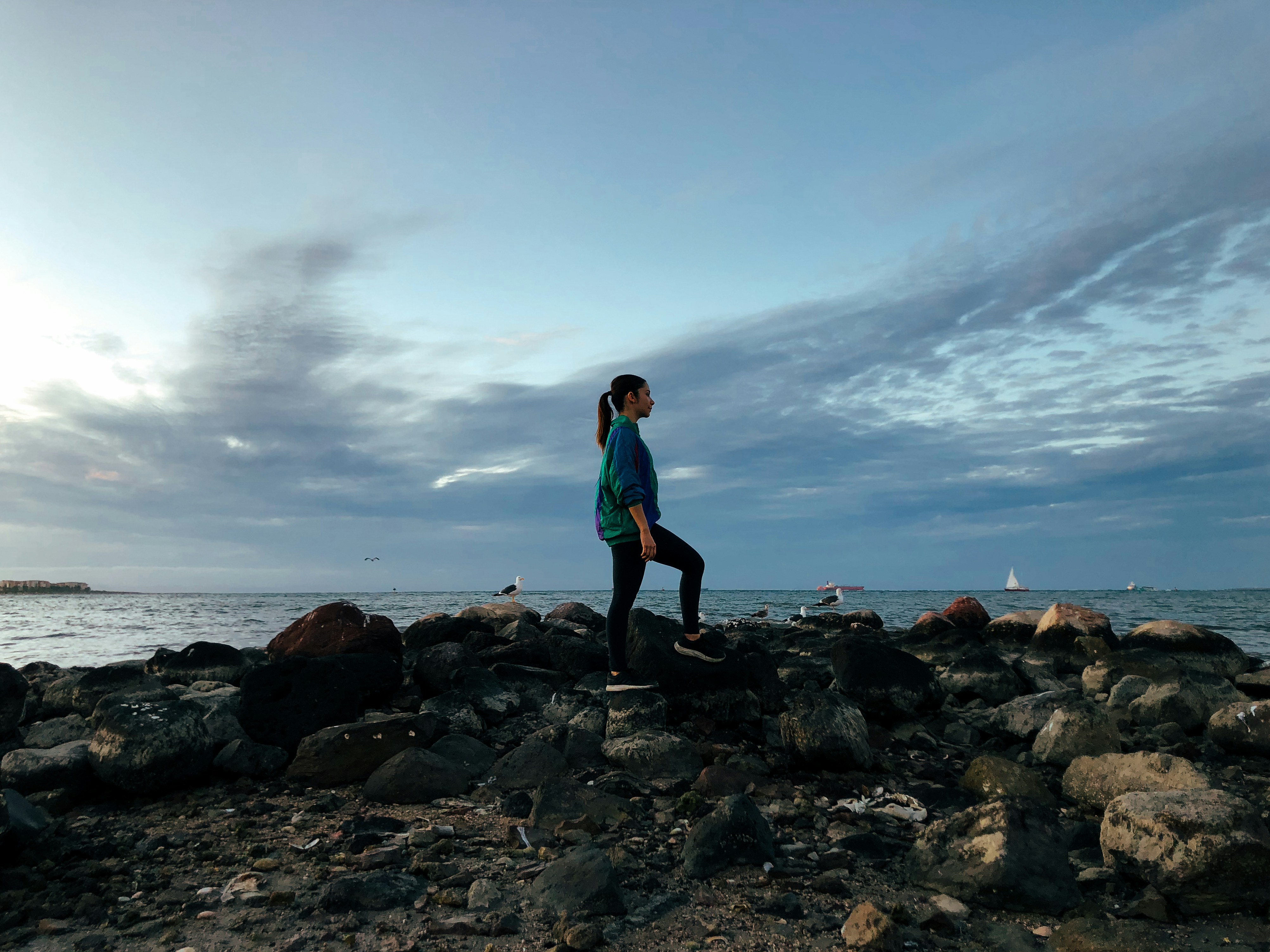a woman standing on a rocky beach next to the ocean