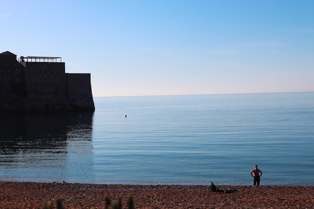 a man standing on a beach next to a body of water