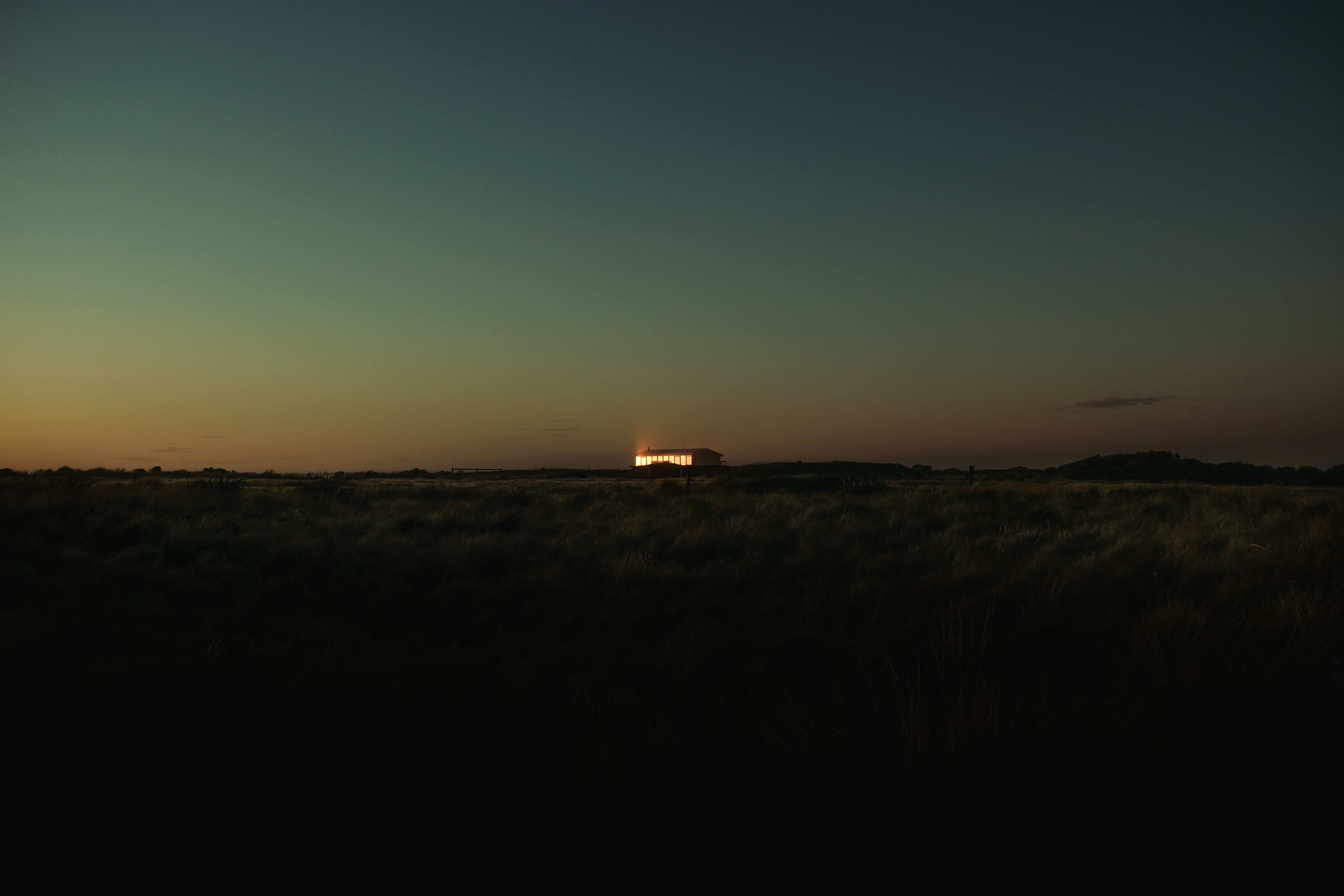 the sun is setting over a field of grass