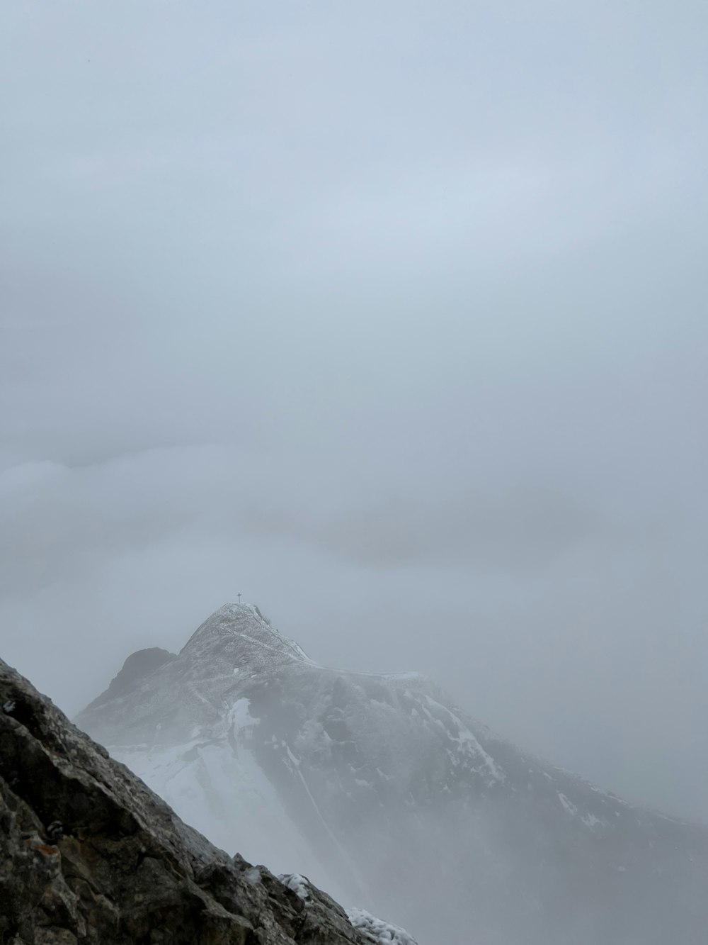 Un uomo in piedi sulla cima di una montagna coperta di neve