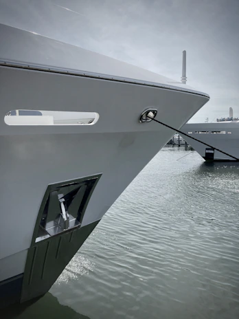 Close-up of a polished yacht bow gently rocking beside a modern marina pier.