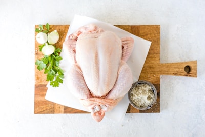 Close-up of fresh organic chicken cuts arranged on rustic wooden board with herbs
