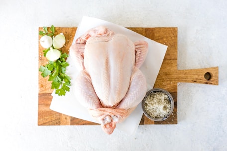 Fresh chicken pieces neatly arranged on a wooden cutting board with herbs.