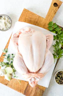 a raw chicken on a cutting board with herbs and seasonings