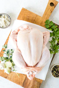 a raw chicken on a cutting board with herbs and seasonings