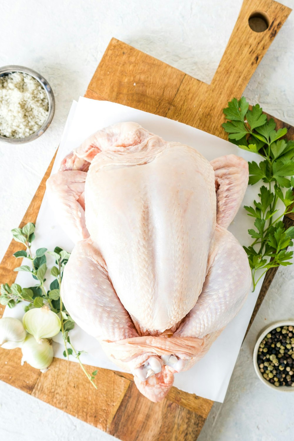 a raw chicken on a cutting board with herbs and seasonings