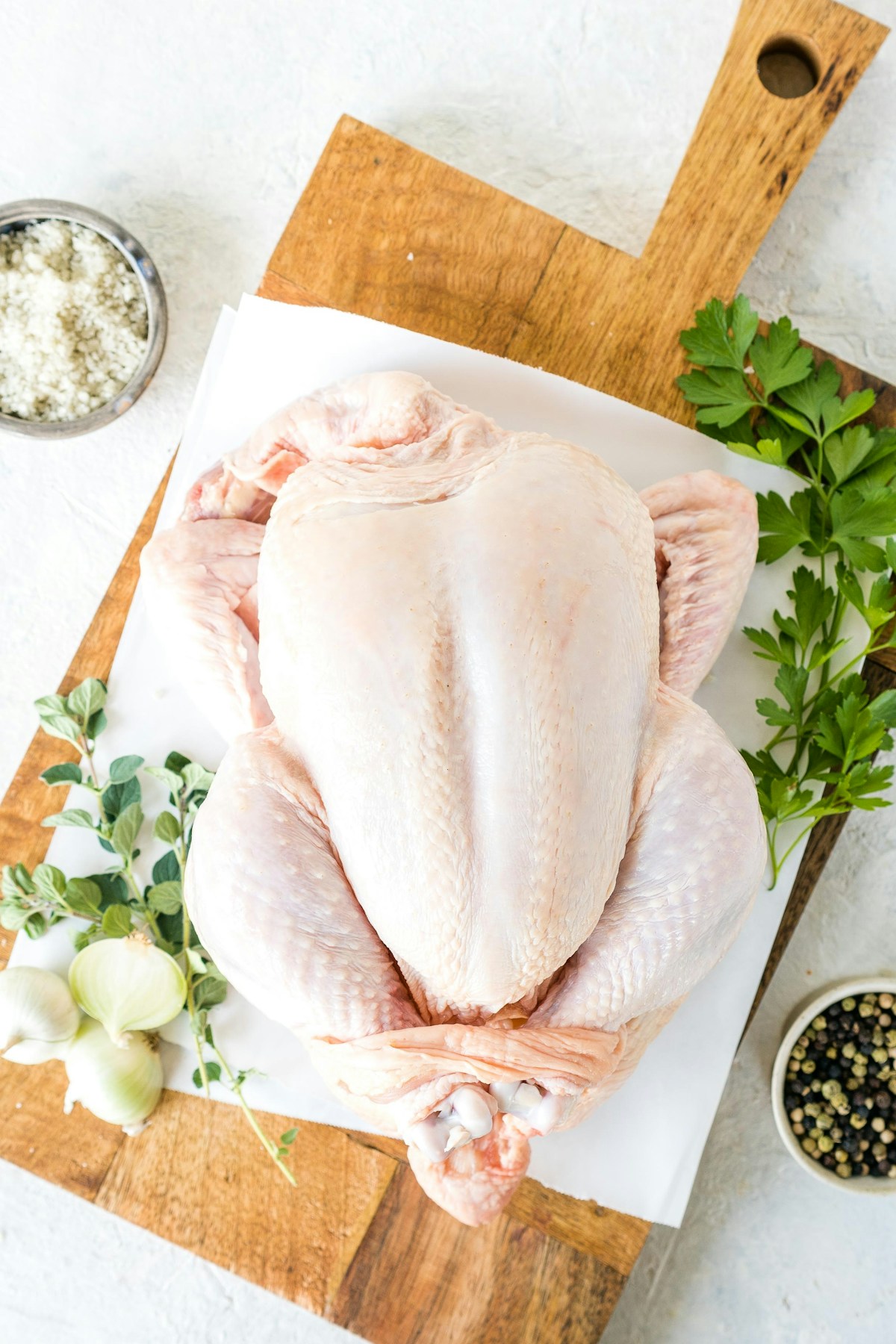 Rohes Poulet mit frischen Kräutern, Zwiebeln und Gewürzen auf einem Holzbrett