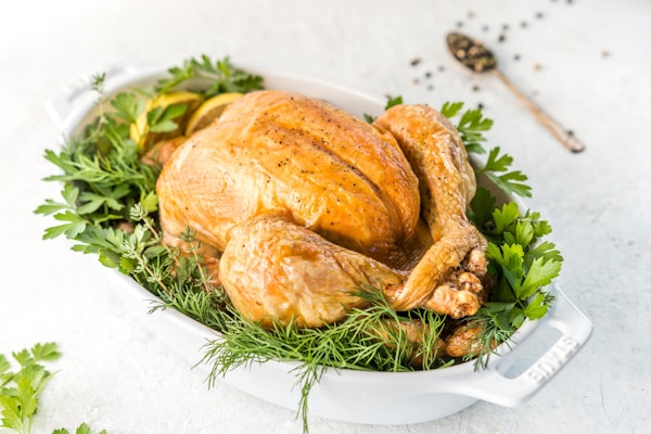 A roasted turkey in a white dish with fresh herbs