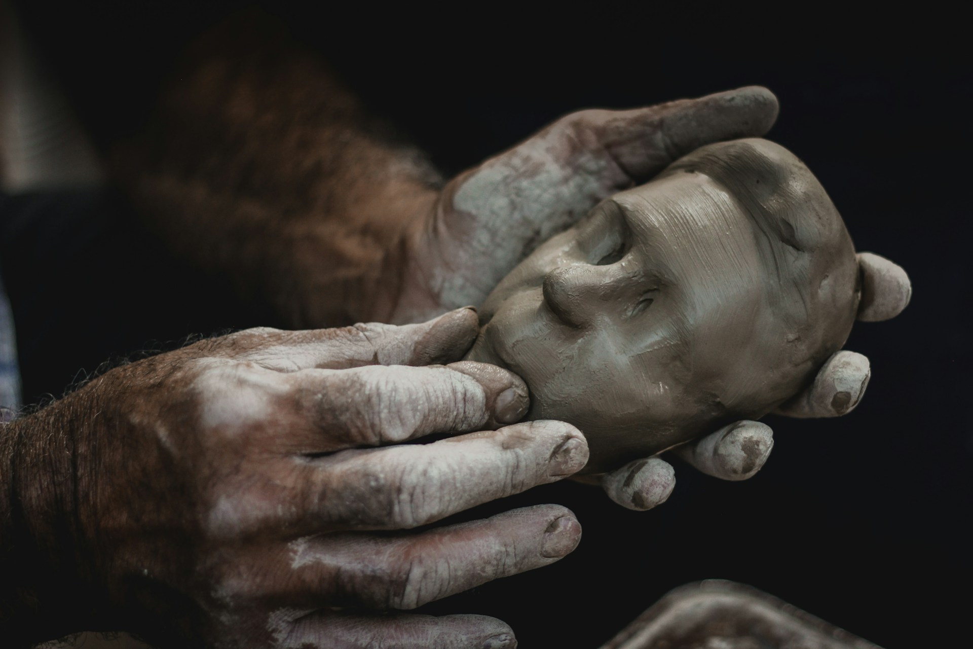 a person holding a clay face in their hands