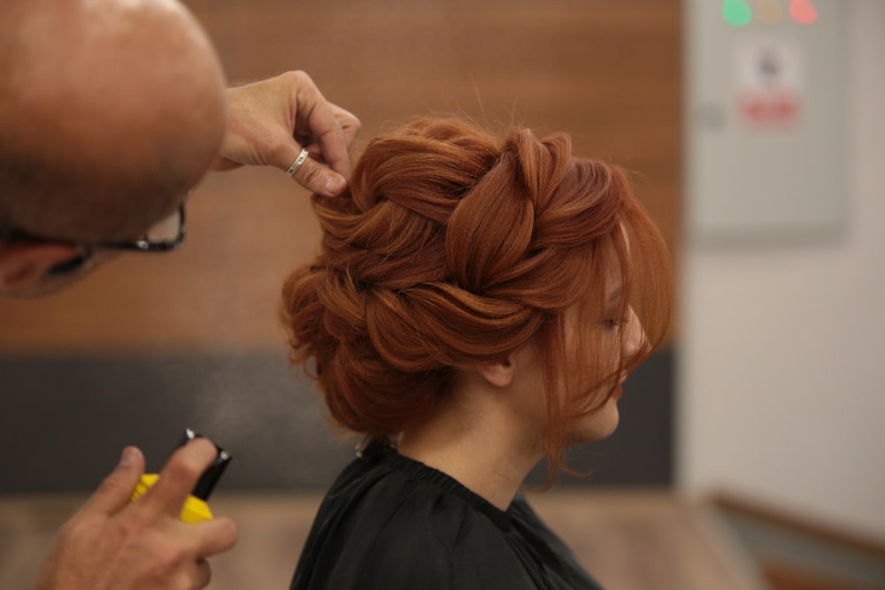 a woman getting her hair styled by a man