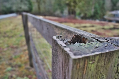 A close-up of a craftsman’s hands repairing a weathered fence post with new hardware.