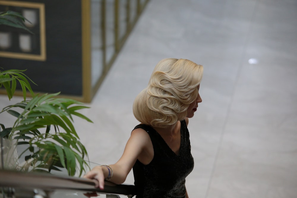a woman in a black dress is walking down the stairs