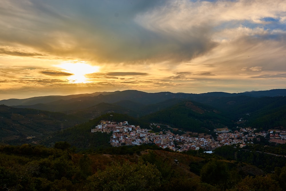 the sun is setting over a small town in the mountains