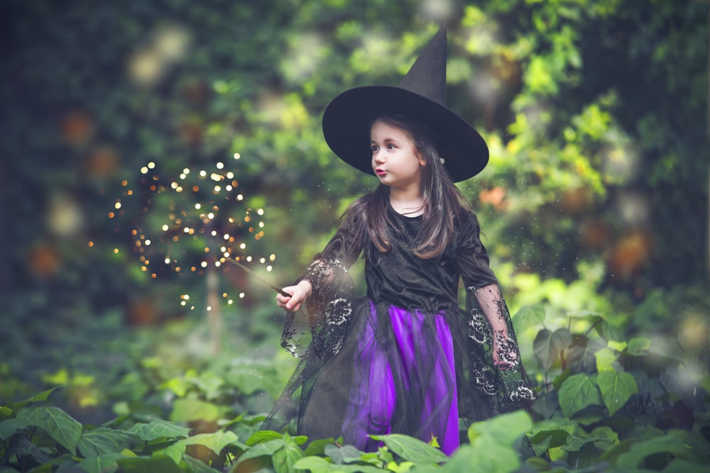 a little girl dressed in a witches costume