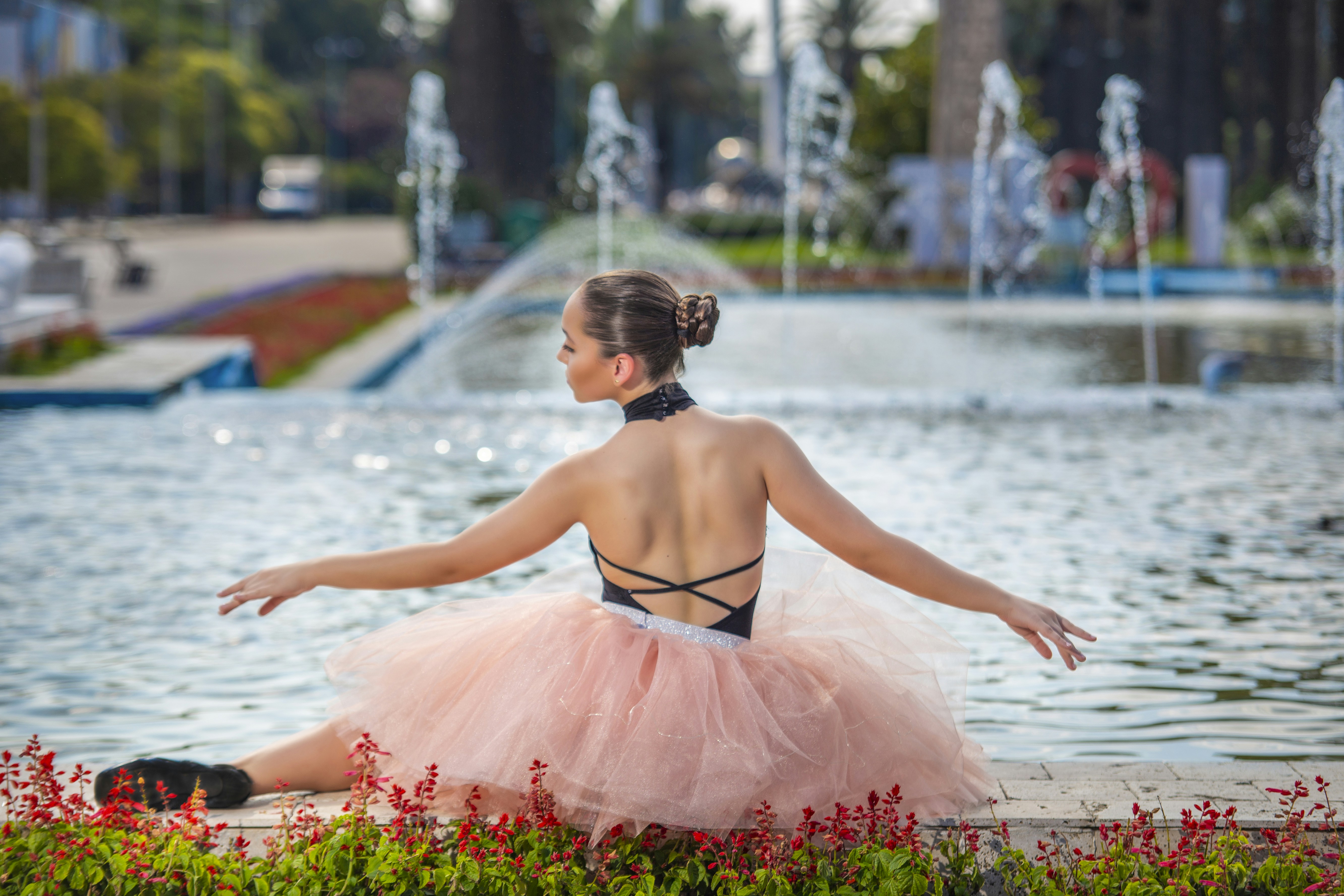 a woman in a pink tutu sitting in front of a fountain