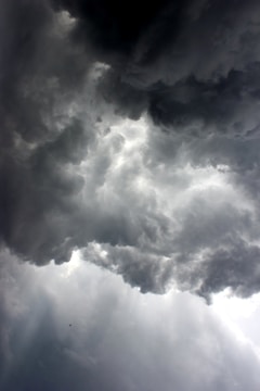 A dark storm cloud shaped like a dollar sign looming over a small, colorful umbrella.