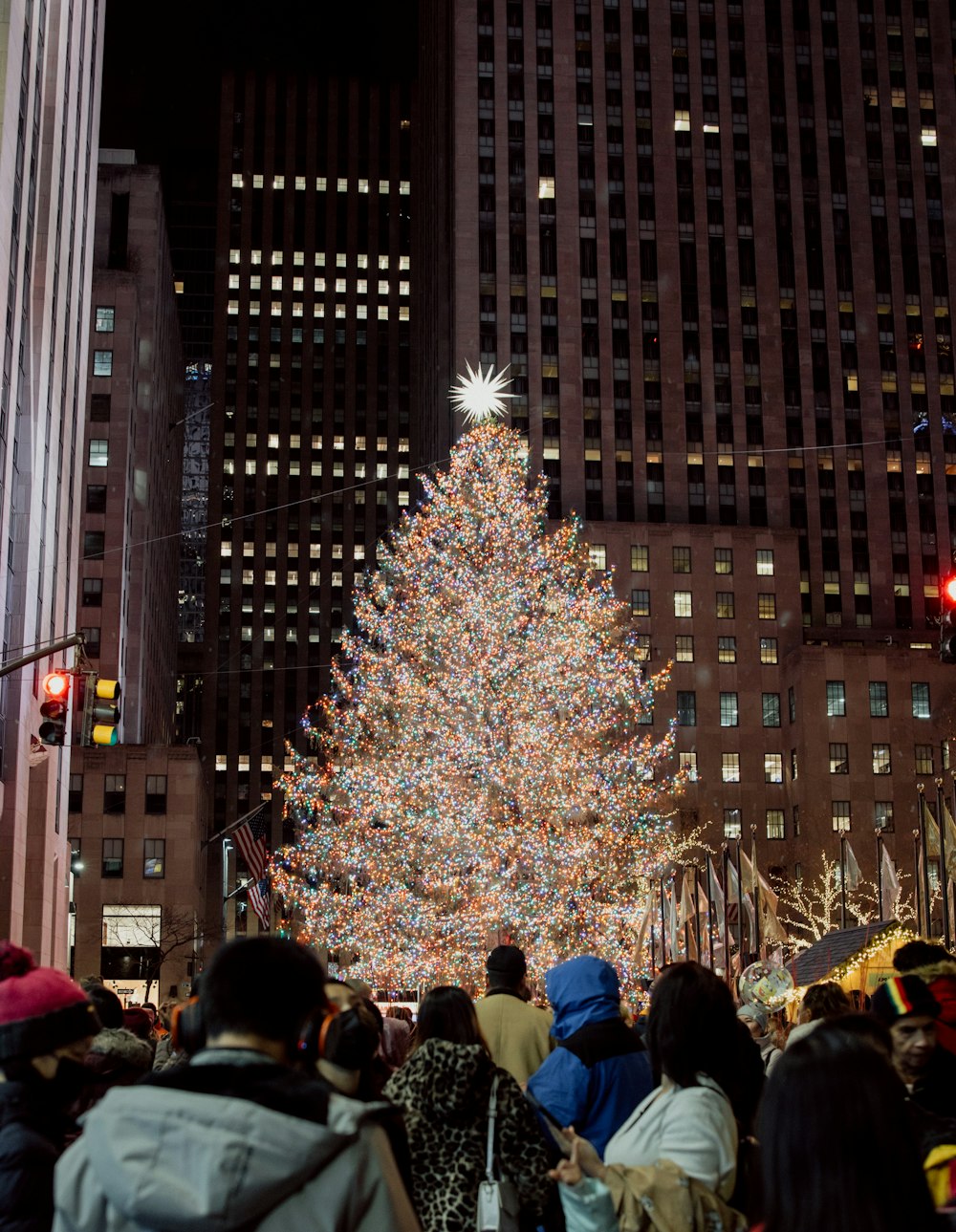 a large christmas tree surrounded by people in a city