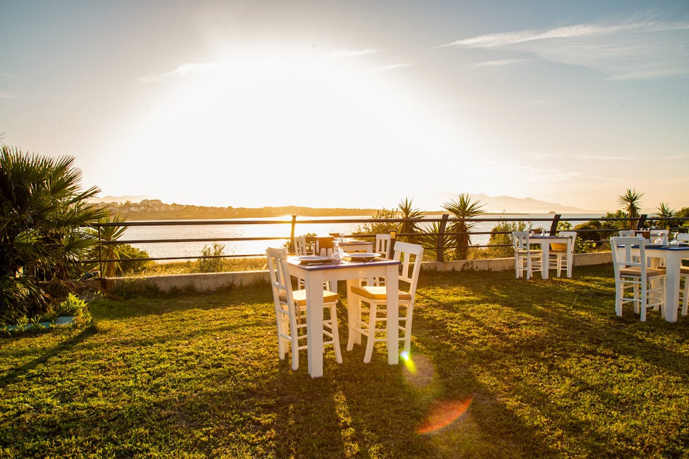 a group of white chairs sitting on top of a lush green field