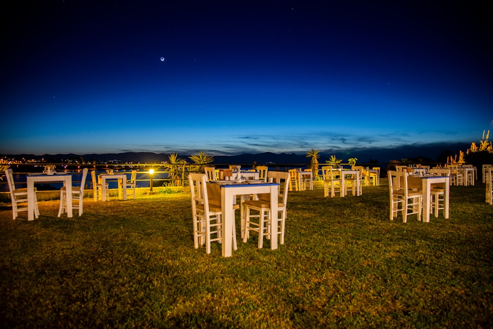 a group of white chairs sitting on top of a lush green field