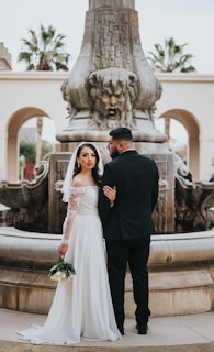 a bride and groom standing in front of a fountain
