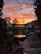 Close-up of a wine glass held up against a backdrop of Australian vineyards at sunset.