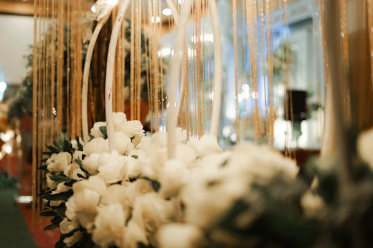 A sophisticated wedding wreath with white flowers and gold accents displayed in a modern showroom.