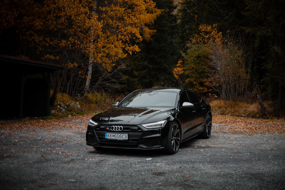 a black car parked in front of a forest