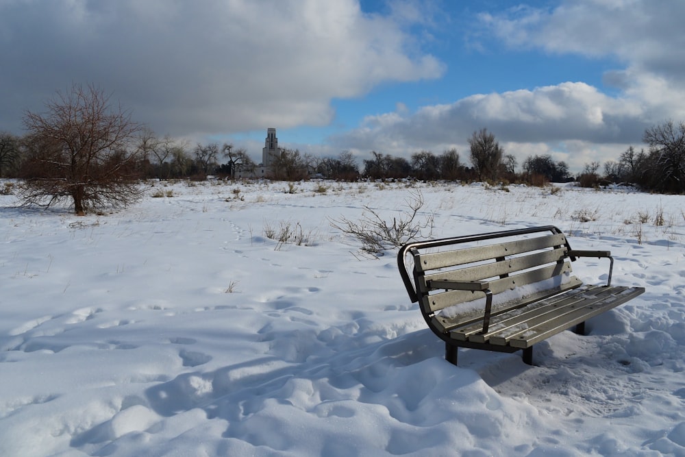 a bench in the middle of a snowy field