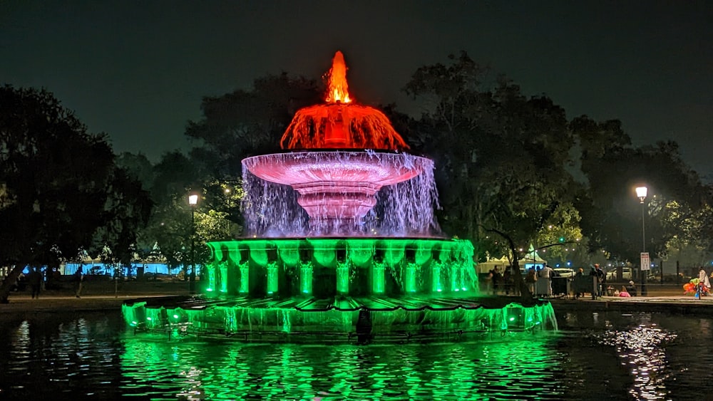 a large fountain with lights on it in the middle of a park