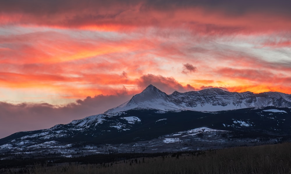 a mountain covered in snow under a cloudy sky