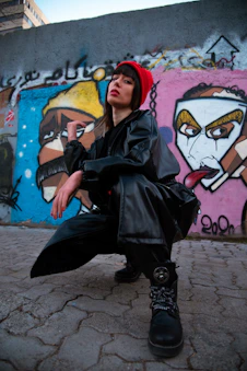 a woman sitting on the ground in front of a wall with graffiti