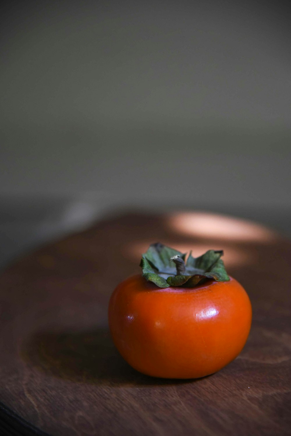 un tomate sentado encima de una tabla de cortar de madera