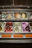 A variety of ice cream tubs in vibrant flavors displayed in a freezer.