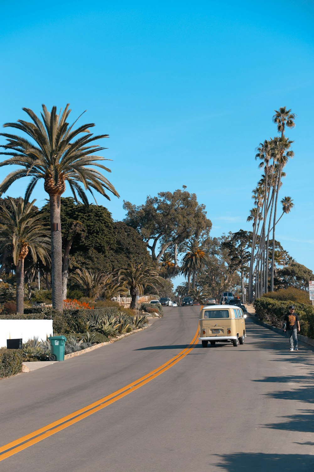 a yellow van driving down a street next to palm trees