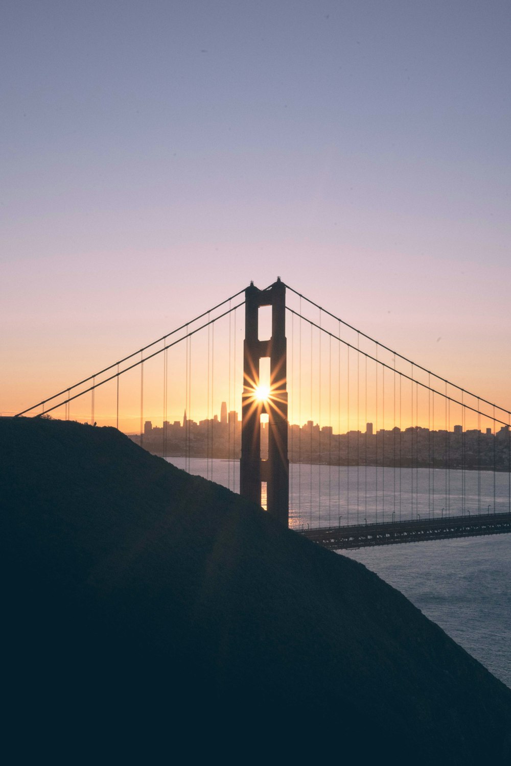 the sun is setting behind the golden gate bridge