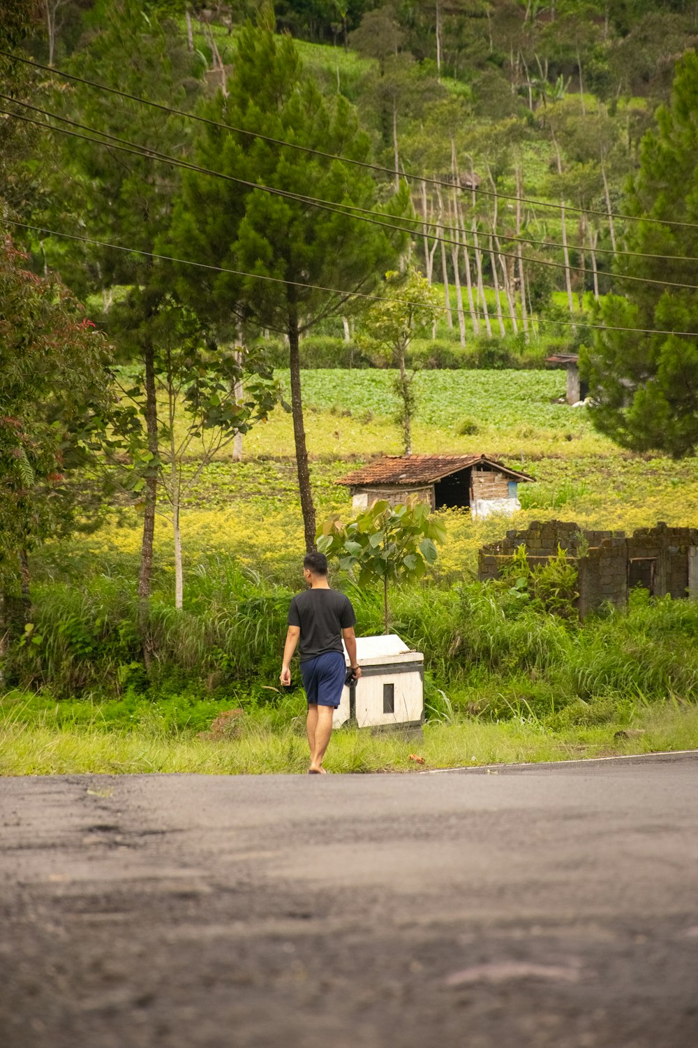 a man walking down the road carrying a cooler