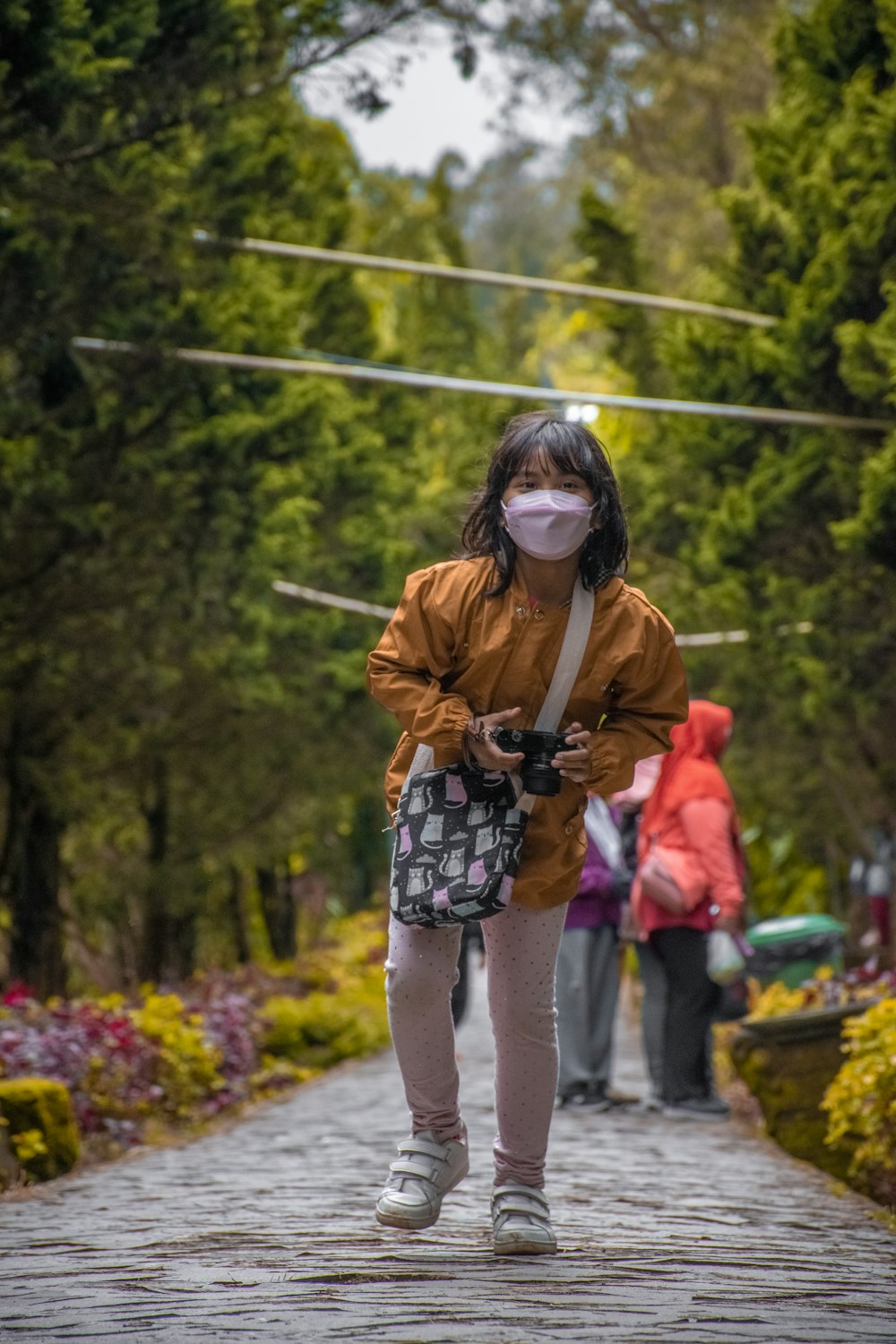 a woman wearing a face mask walks down a path