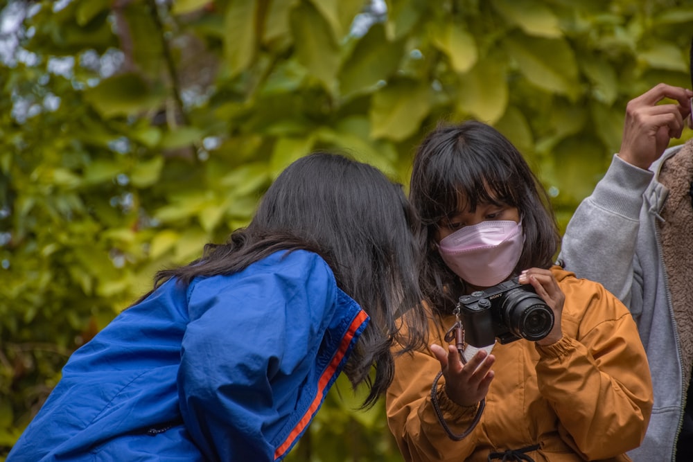 three people wearing face masks and taking pictures