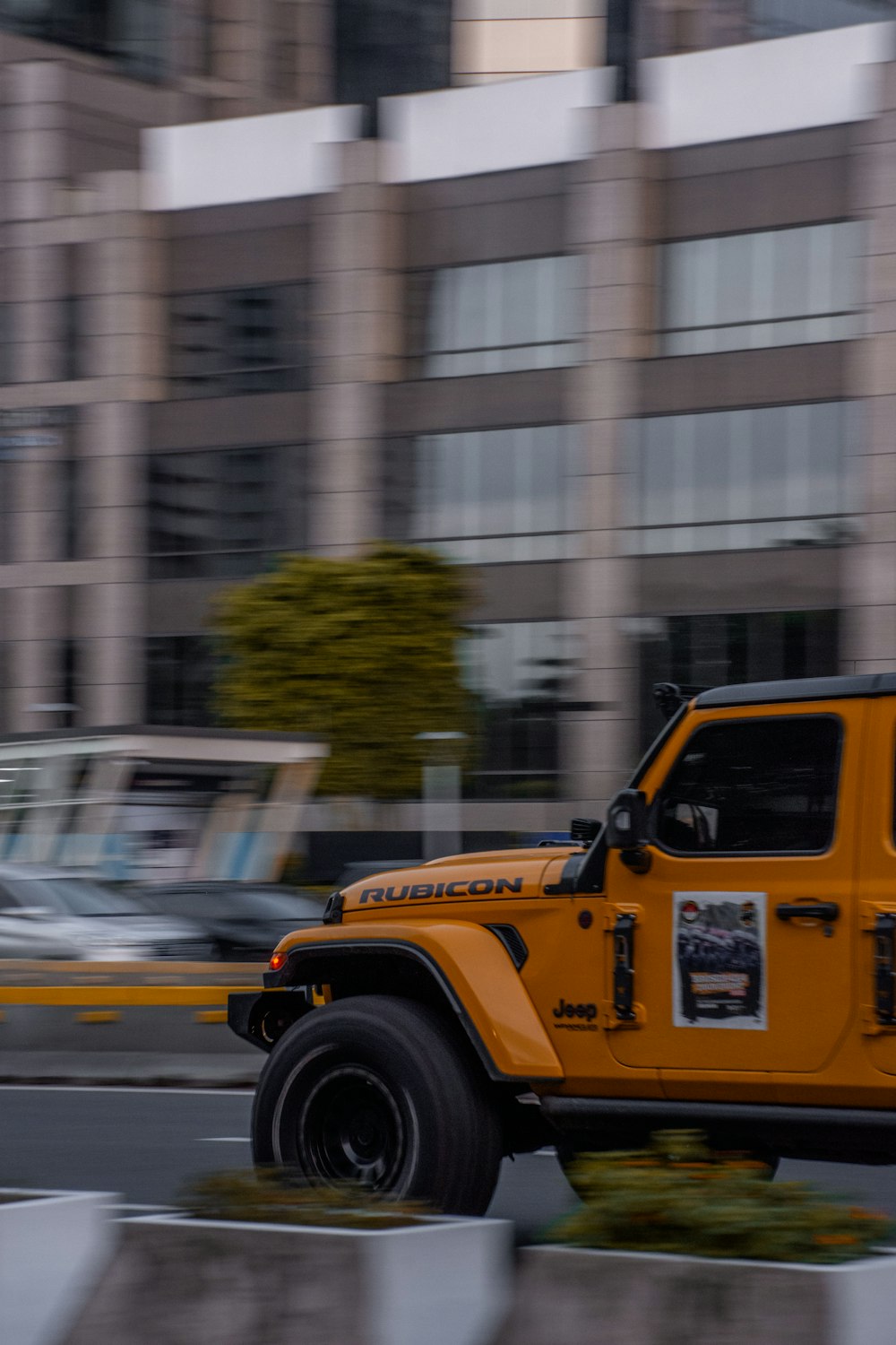 a yellow jeep driving down a street next to tall buildings