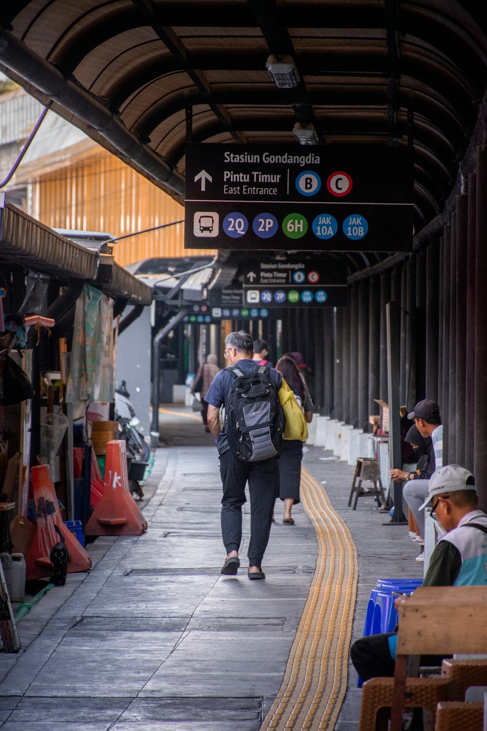 a group of people walking down a sidewalk next to a train