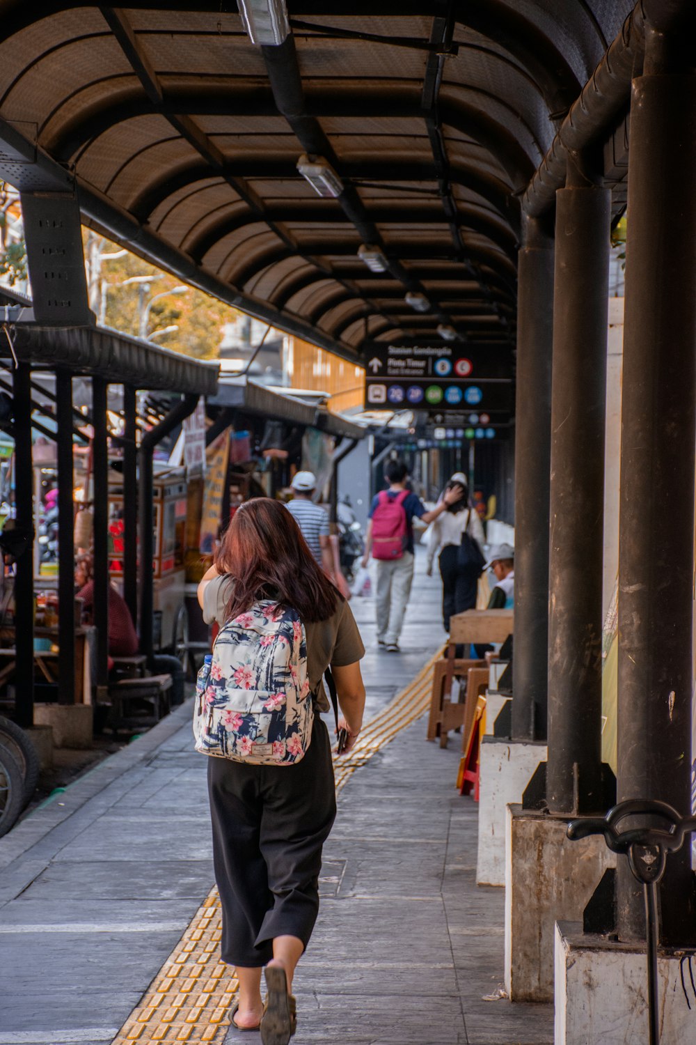 a woman walking down a sidewalk next to a train